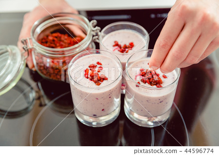 A person adding toppings over the smoothie A person adding toppings over the smoothie 44596774