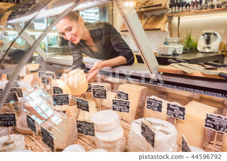 Shop clerk woman sorting cheese in the supermarket display 44596792