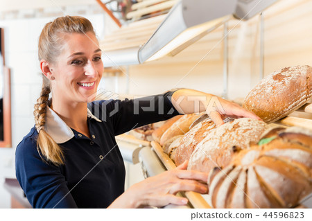 Bakery woman putting bread in shop shelf Bakery woman putting bread in shop shelf 44596823