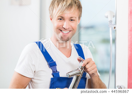 Portrait of a cheerful maintenance worker holding a faucet in a Portrait of a cheerful maintenance worker holding a faucet in a 44596867