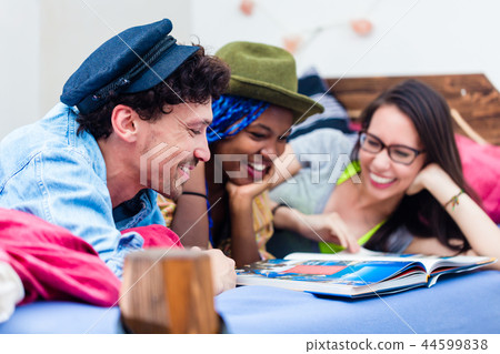 Man lying with friends looking at photo album Man lying with friends looking at photo album 44599838
