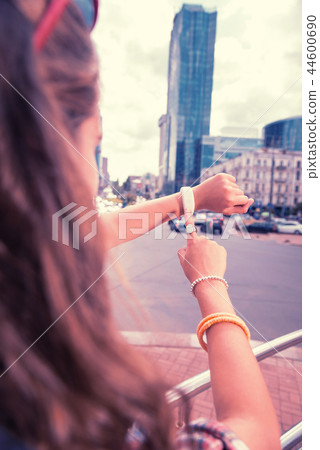 Dark-haired woman wearing ring and bracelets on her right hand checking time 44600690