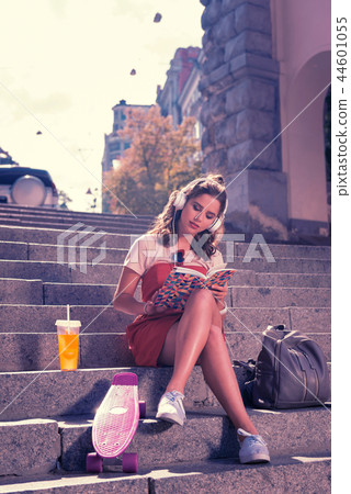 Young student girl sitting and reading book while waiting for her boyfriend Young student girl sitting and reading book while waiting for her boyfriend 44601055