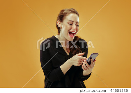 Young beautiful woman using mobile phone studio on gold color background 44601386