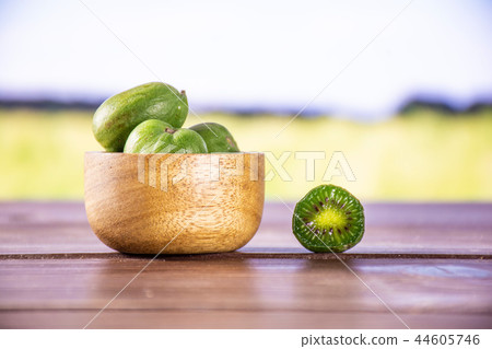 Fresh green mini baby kiwi fruit with field behind Fresh green mini baby kiwi fruit with field behind 44605746