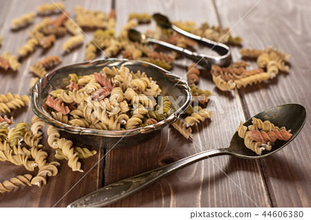 Raw pasta fusilli on brown wood Raw pasta fusilli on brown wood 44606380