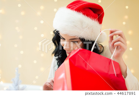 Happy young woman with santa hat holding a shopping bag 44617891