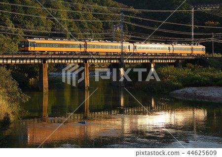 A Kintetsu Limited Express train shining in the setting sun, reflected on the water's surface | A dramatic railway scene A Kintetsu Limited Express train shining in the setting sun, reflected on the water's surface | A dramatic railway scene 44625609