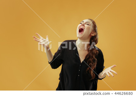 The young emotional angry woman screaming on gold studio background The young emotional angry woman screaming on gold studio background 44626680