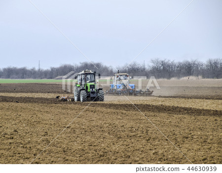 Lush and loosen the soil on the field before sowing. The tractor plows a field with a plow 44630939