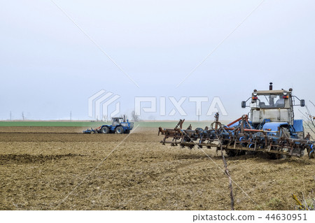 Lush and loosen the soil on the field before sowing. The tractor plows a field with a plow 44630951