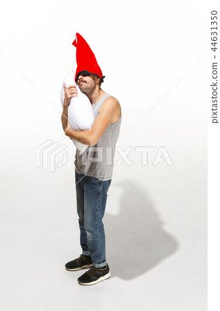 Vertical shot of a content young man hugging a white pillow Vertical shot of a content young man hugging a white pillow 44631350