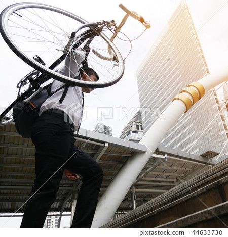 Businessman carrying a bicycle on a walkway street 44633730
