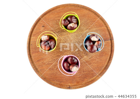 Colorful buckets with chestnuts on wooden plate 44634355