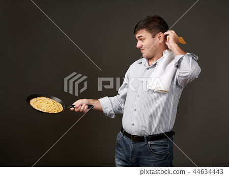 man posing with a pancake in pan, gray background 44634443