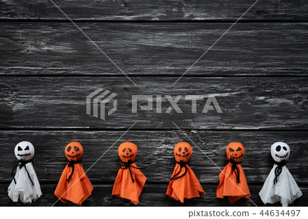 White and orange paper ghost on wooden background 44634497