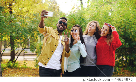 African American student is taking selfie with beautiful girls Asian and Caucasian standing in park African American student is taking selfie with beautiful girls Asian and Caucasian standing in park 44634973
