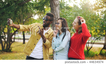 Stylish young people man and women are taking selfie wearing sunglasses posing and smiling holding Stylish young people man and women are taking selfie wearing sunglasses posing and smiling holding 44634974