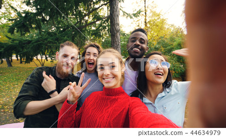Point of view shot of young woman holding device with camera and taking selfie with friends multi Point of view shot of young woman holding device with camera and taking selfie with friends multi 44634979