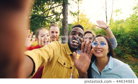 Point of view shot of cheerful students making online video call calling friends holding device Point of view shot of cheerful students making online video call calling friends holding device 44634981