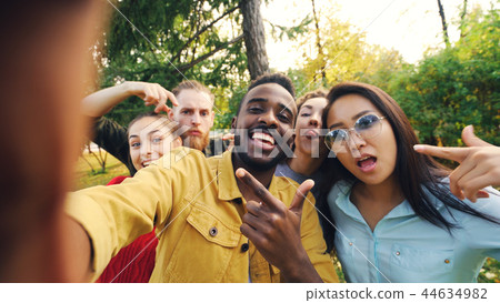 Point of view shot of friends taking selfie in park looking at camera, making funny faces and Point of view shot of friends taking selfie in park looking at camera, making funny faces and 44634982