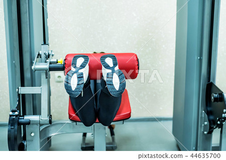 Young woman does leg exercises in gym lying Young woman does leg exercises in gym lying 44635700