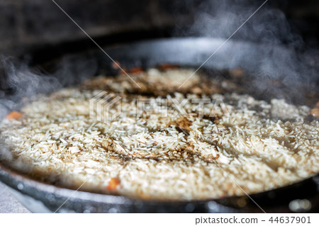 cooking Rice for pilaw or paella in iron cauldron over open fire. Smoke and steam. Tasty food 44637901