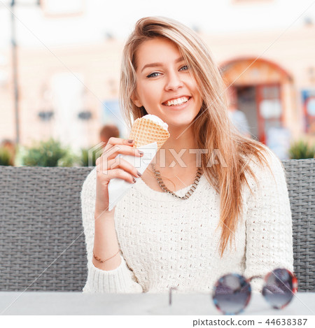 Girl eating an ice-cream scoop in a waffle cone Girl eating an ice-cream scoop in a waffle cone 44638387