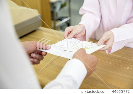The man's hand holding a prescription and a slipbook to a dispensing pharmacy 44655772