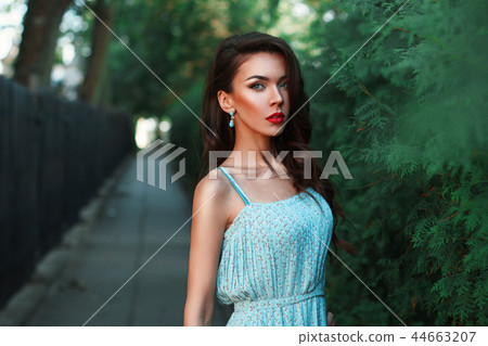 Woman walking in the park in a turquoise dress Woman walking in the park in a turquoise dress 44663207