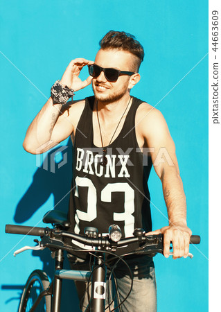 Hipster with a bike  near a bright blue wall. 44663609
