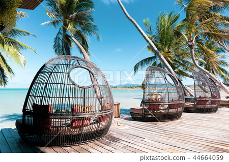 Rattan chair on wooden deck by the beach Rattan chair on wooden deck by the beach 44664059