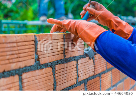 Hand of construction worker laying down brick wall Hand of construction worker laying down brick wall 44664080