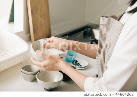 Young housewife's hand wiping dishes with a cloth Young housewife's hand wiping dishes with a cloth 44664262