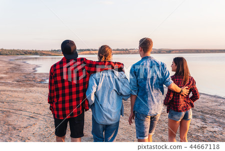 friends on beach together walking during sunset 44667118