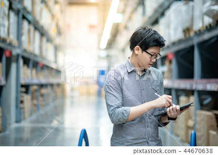 Asian man doing stocktaking on tablet in warehouse Asian man doing stocktaking on tablet in warehouse 44670638