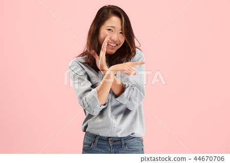 The young woman whispering a secret behind her hand over pink background 44670706
