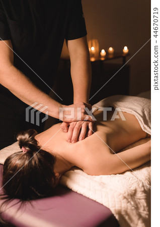 Close up Male manual worker doing spa massage to a young girl in a dark room Close up Male manual worker doing spa massage to a young girl in a dark room 44670719