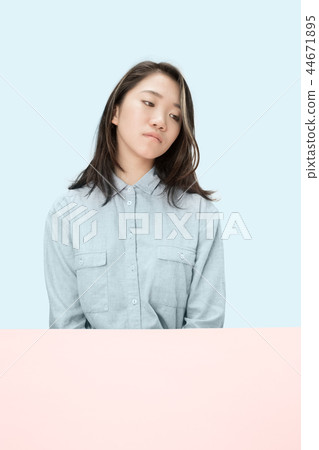 The serious business woman sitting and looking down against blue background. 44671895