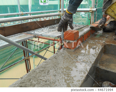 Workers laying brick to form brick wall Workers laying brick to form brick wall 44671994