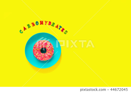 Carbohydrates and pink donut on plate on yellow  44672045