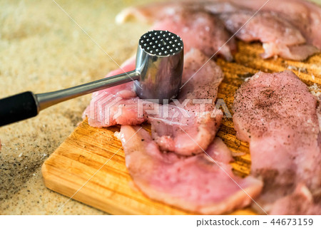 Pounding raw meat with metal hammer close Pounding raw meat with metal hammer close 44673159