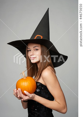 Closeup of playful Halloween witch holding pumpkins 44675650