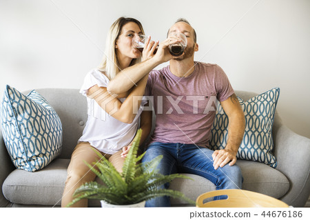 Relaxed young couple watching tv and drinking beer at home 44676186