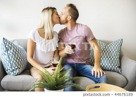 Relaxed young couple watching tv and drinking beer at home Relaxed young couple watching tv and drinking beer at home 44676189