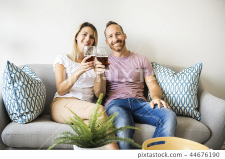 Relaxed young couple watching tv and drinking beer at home Relaxed young couple watching tv and drinking beer at home 44676190