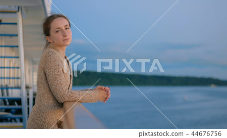 Woman admiring landscape from deck of cruise ship after sunset Woman admiring landscape from deck of cruise ship after sunset 44676756