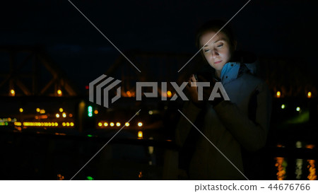 Woman using vertical smartphone on deck of cruise ship at night 44676766