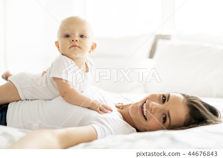 mother with baby on bed having good time mother with baby on bed having good time 44676843