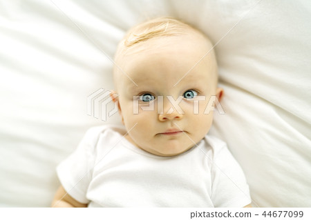 Cute baby girl lying on white sheet at home Cute baby girl lying on white sheet at home 44677099